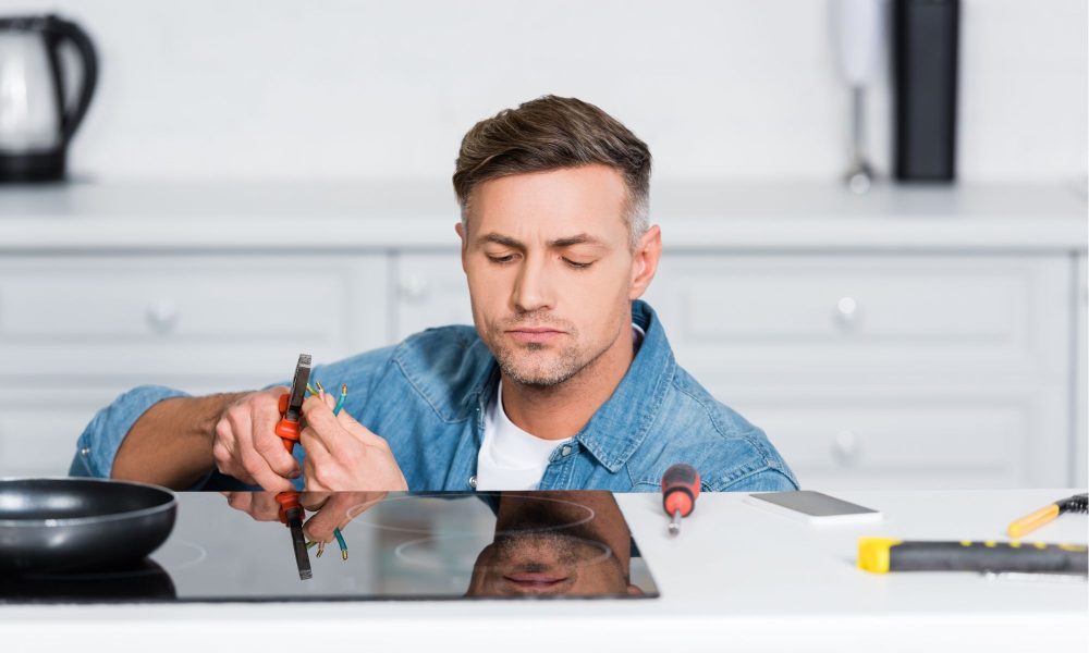 handsome man repairing electric stove at kitchen